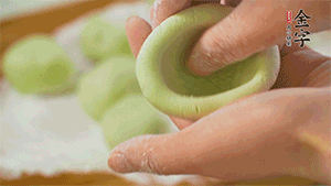 將均分的艾草面團搓成圓，挖一個窩，放入餡心，再搓成圓。