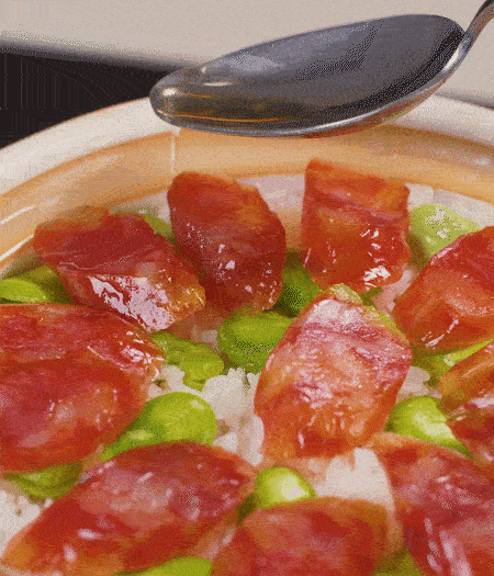 大米出現(xiàn)小孔時開蓋放香腸，往鍋邊淋入少許油，再燜煮8~10分鐘左右。