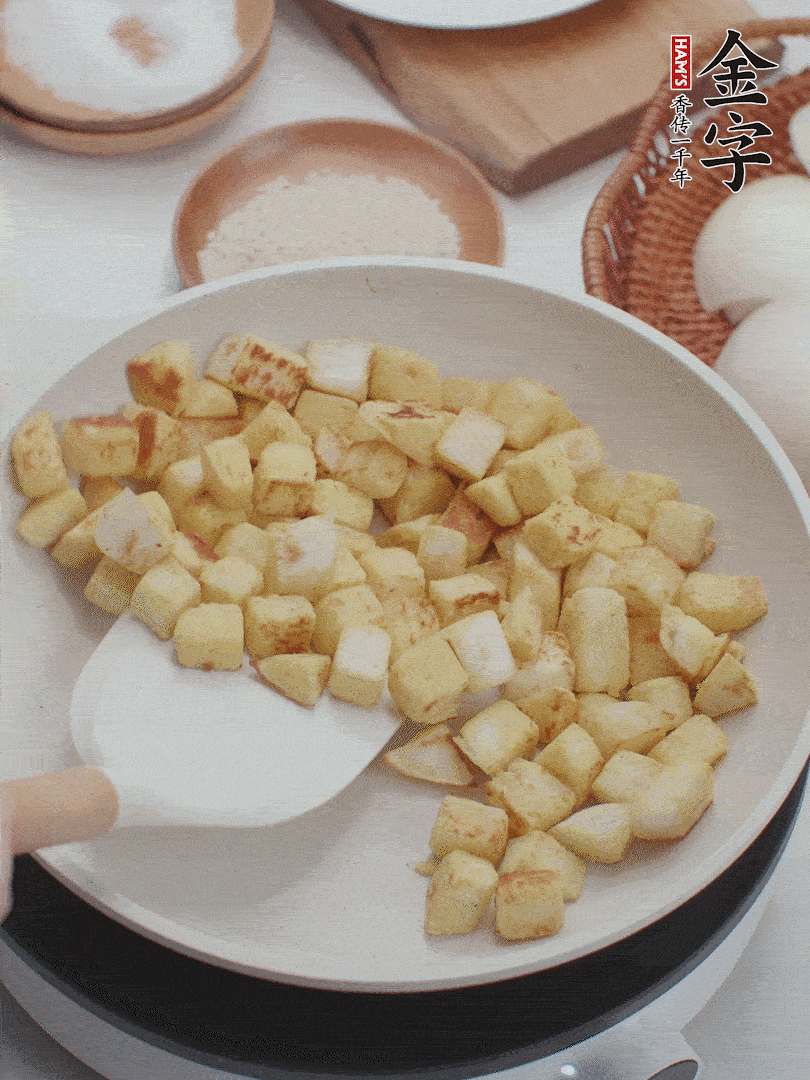 起鍋熱油，倒入饅頭丁，小火煎至蛋液凝固定型再翻面，饅頭丁部煎至金黃時(shí)盛起待用。